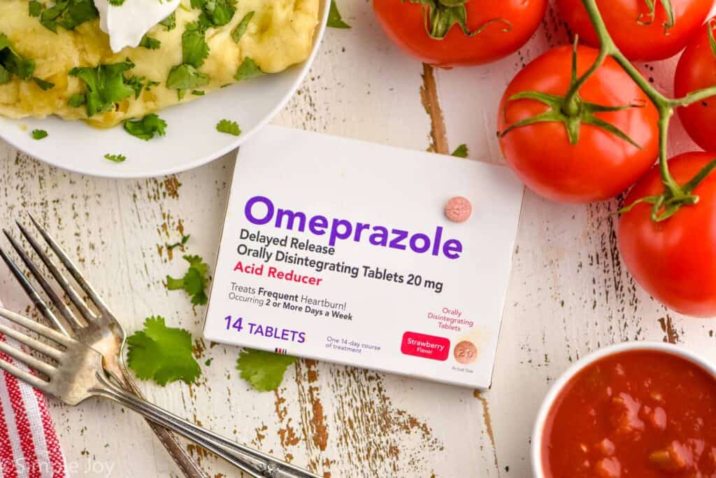 overhead of a box of omeprazole odd with a pill on it next to tomatos