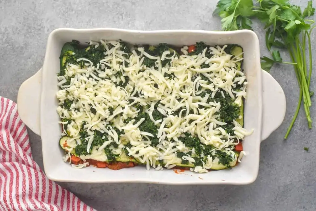 overhead view of zucchini lasagna being put together, can see shredded mozzarella on top of spinach later