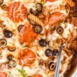 overhead photo of a pizza casserole in a skillet with a serving spoon