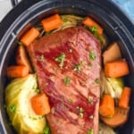 pinterest graphic of overhead photo of corned beef recipe with cabbage, carrots, and potatoes in a crockpot