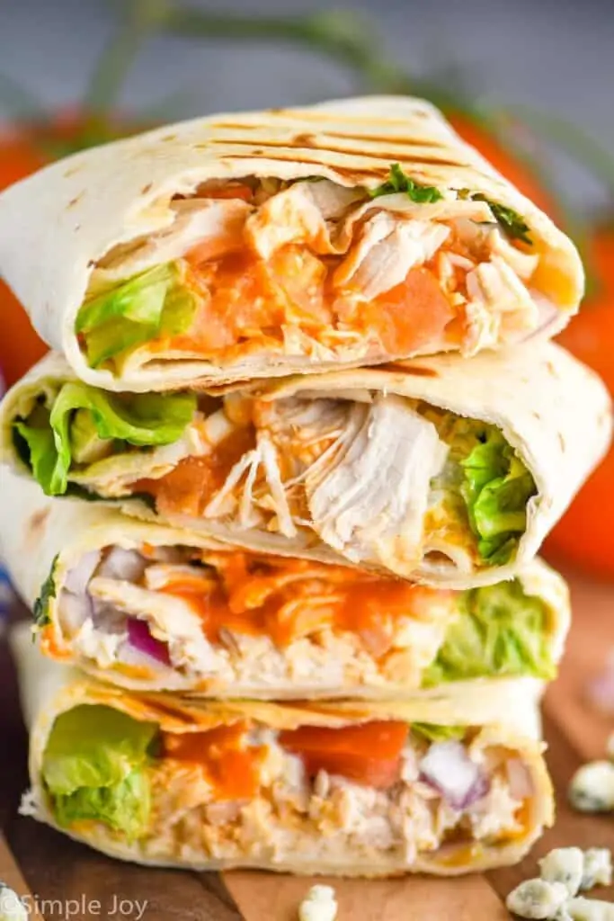 stack of buffalo chicken wraps on a cutting board that have been cut in half to see the insides