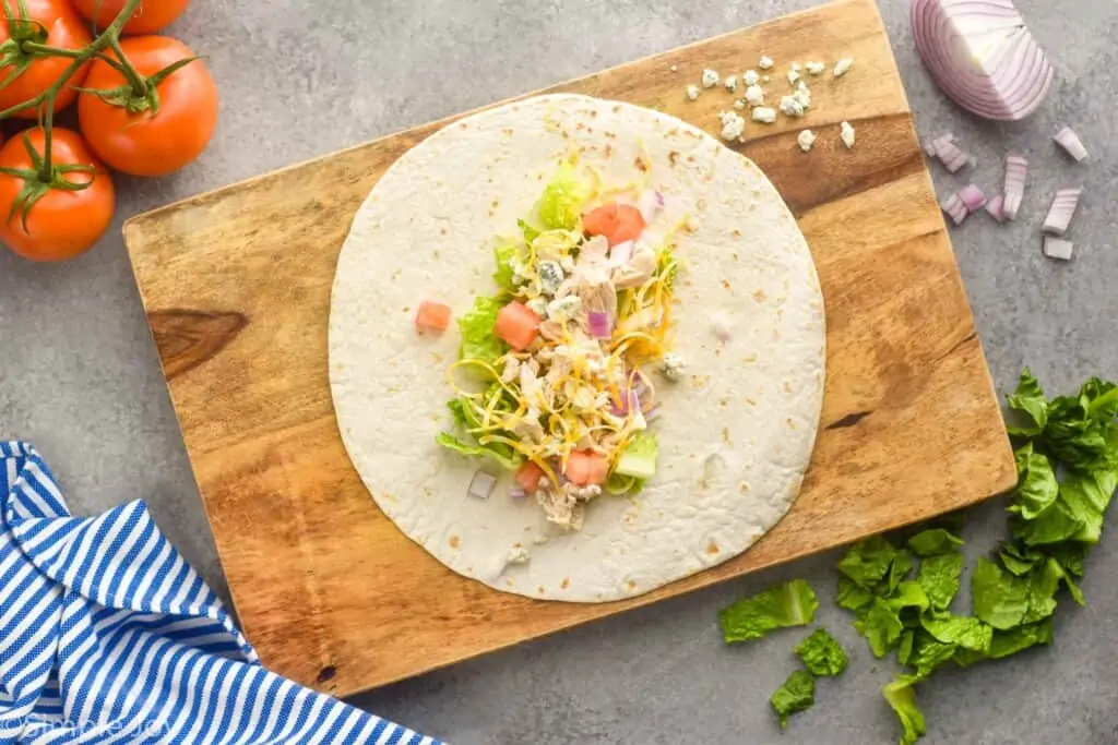 overhead view of a tortilla with ingredients for a chicken wrap