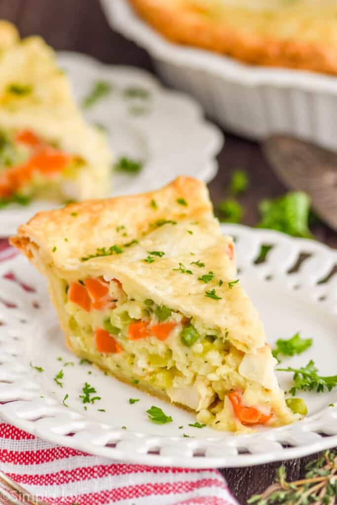 a piece of homemade chicken pot pie on a white plate garnished with fresh parsley