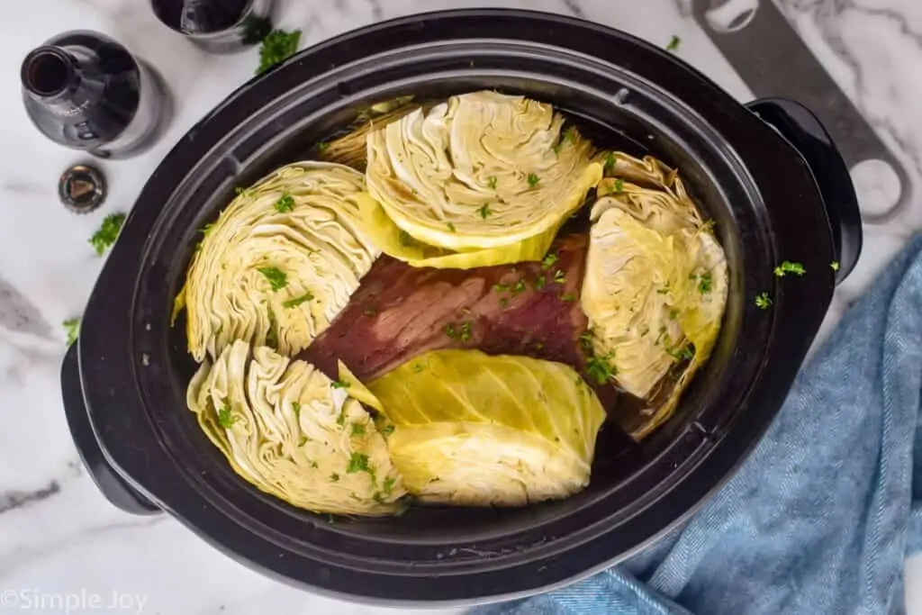 overhead photo of cabbage covering corned beef in a crockpot