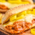 close up of a crockpot buffalo chicken sandwich on a hoagie roll with melted cheese and pepper rings