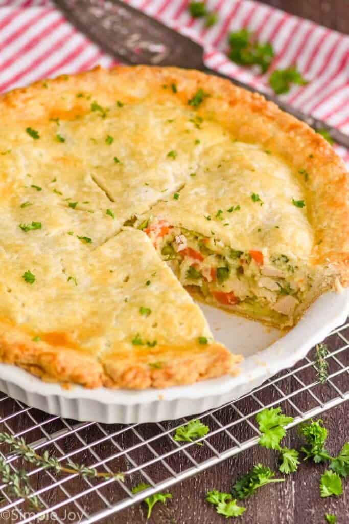 a pie plate full of easy chicken pot pie with a piece missing, garnished with parsley