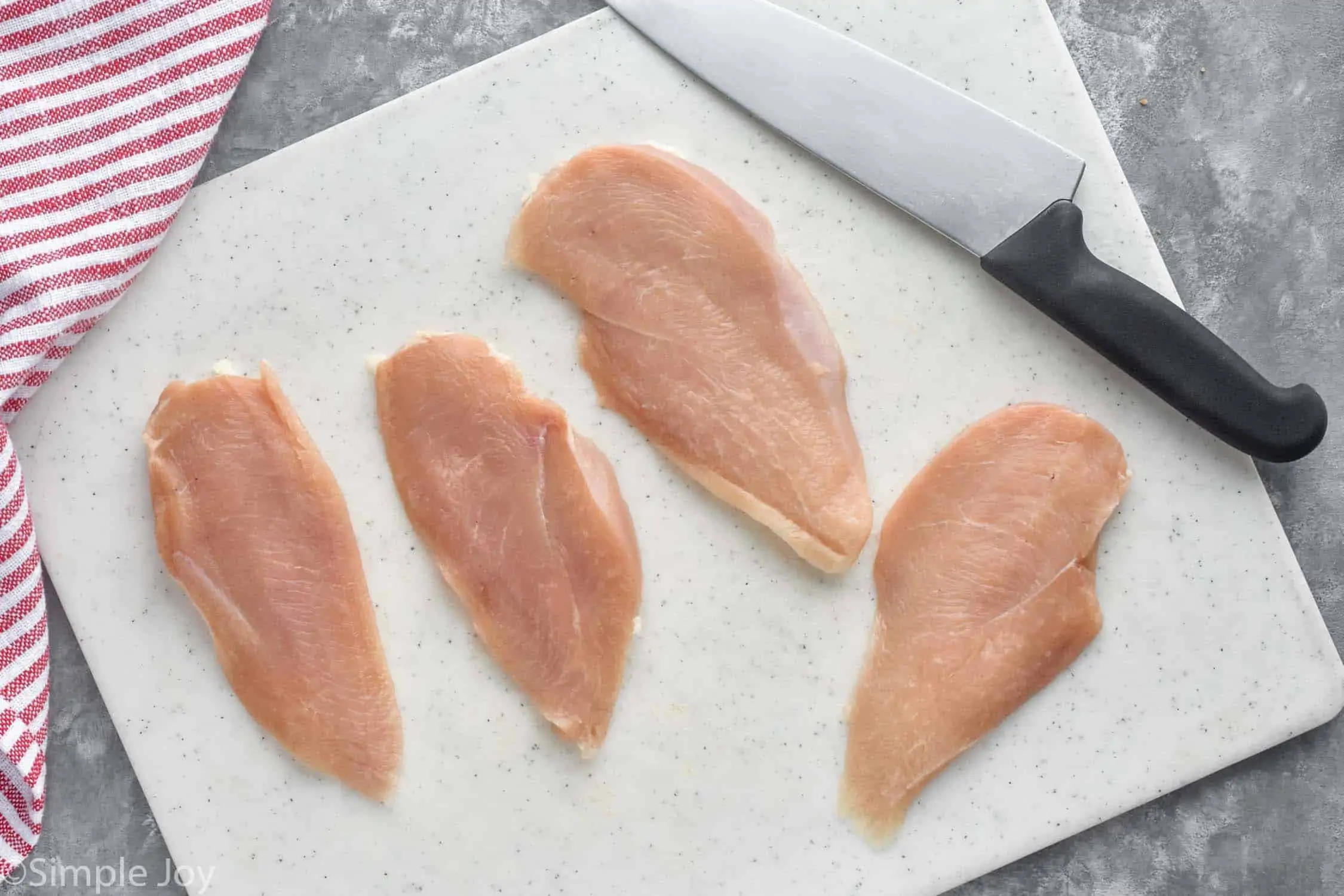 overhead view of four chicken cutlets on a cutting board