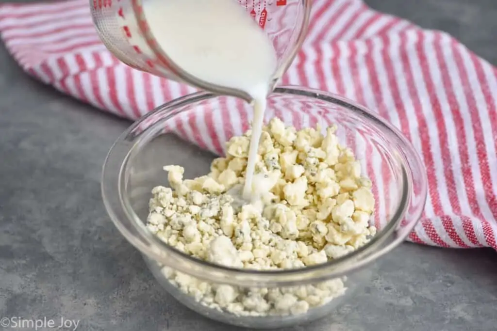 milk mixture being poured over a bowl of blue cheese