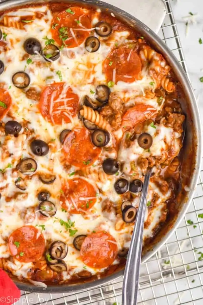 overhead photo of a pizza casserole in a skillet with a serving spoon