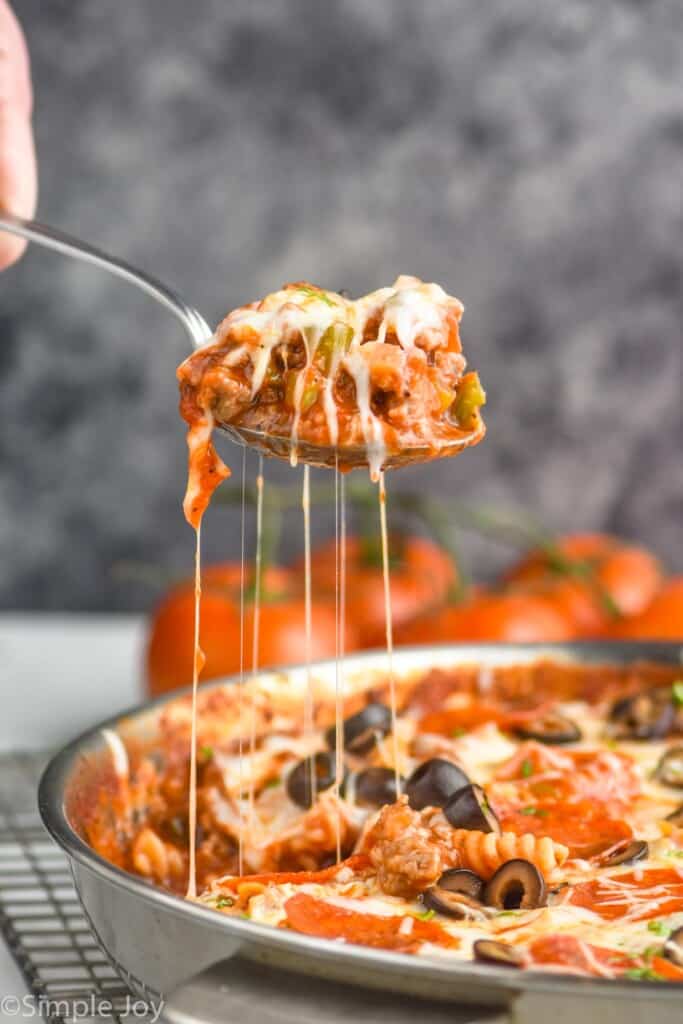 serving spoon pulling up a scoop of pizza casserole, with cheese hanging down