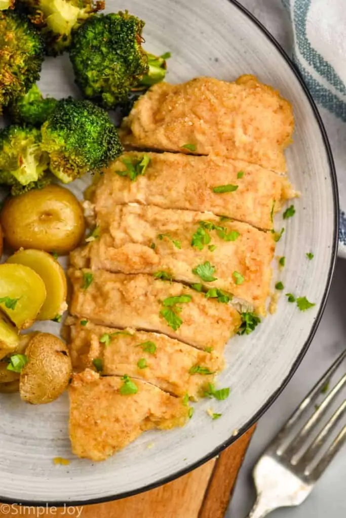 plate with a piece of sour cream chicken cut into slices next to broccoli and roasted potatoes