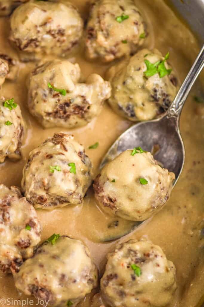 close up of a spoon dishing up a Swedish meatball out of a pan
