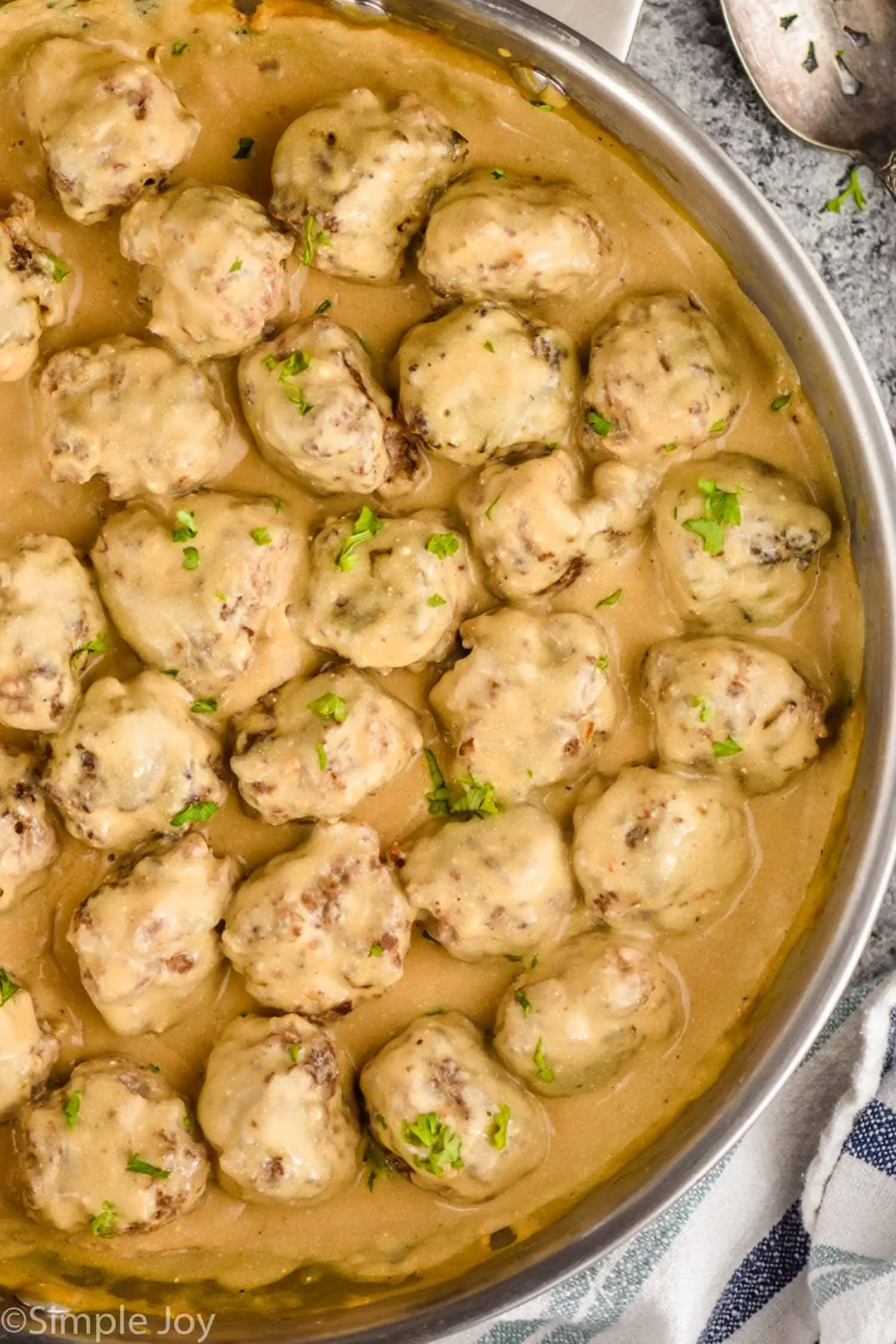 overhead of a pan of Swedish meatballs in gravy garnished with parsley