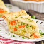 a piece of chicken pot pie on a white plate garnished with parsley