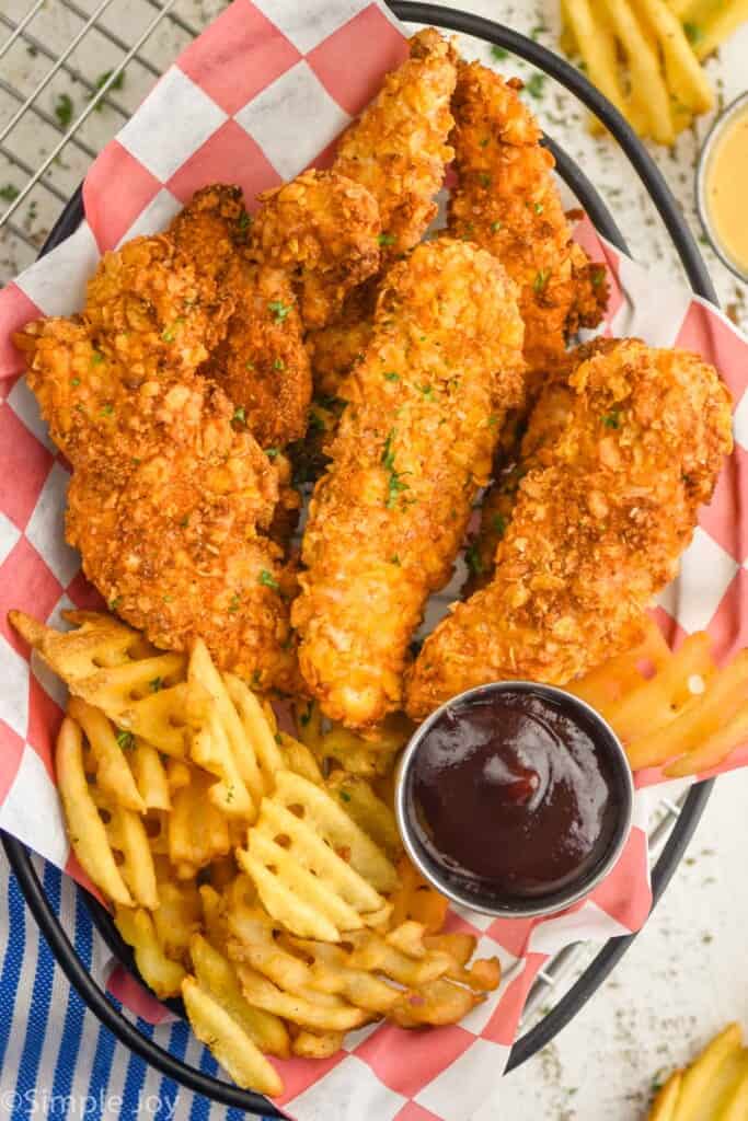 overhead view of air fryer chicken tenders in a basket with fries
