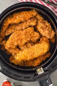 overhead view of breaded chicken tenders in an air fryer basket