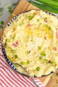 close up overhead of a bowl of colcannon with two pads of butter and diced scallions