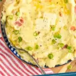 Pinterest graphic showing close up overhead of a bowl of colcannon with two pads of butter and diced scallions