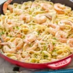 pinterest graphic of side view of a red skillet full of shrimp pasta recipe garnished with parmesan and parsley