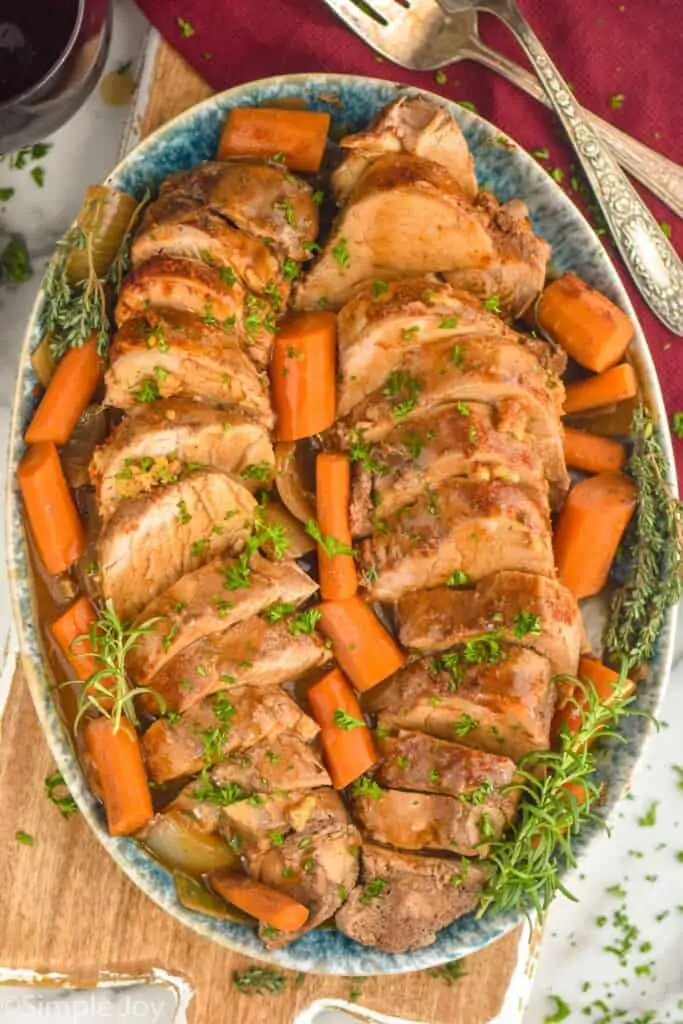 overhead of slow cooker pork tenderloin sliced an on a platter with cooked carrots