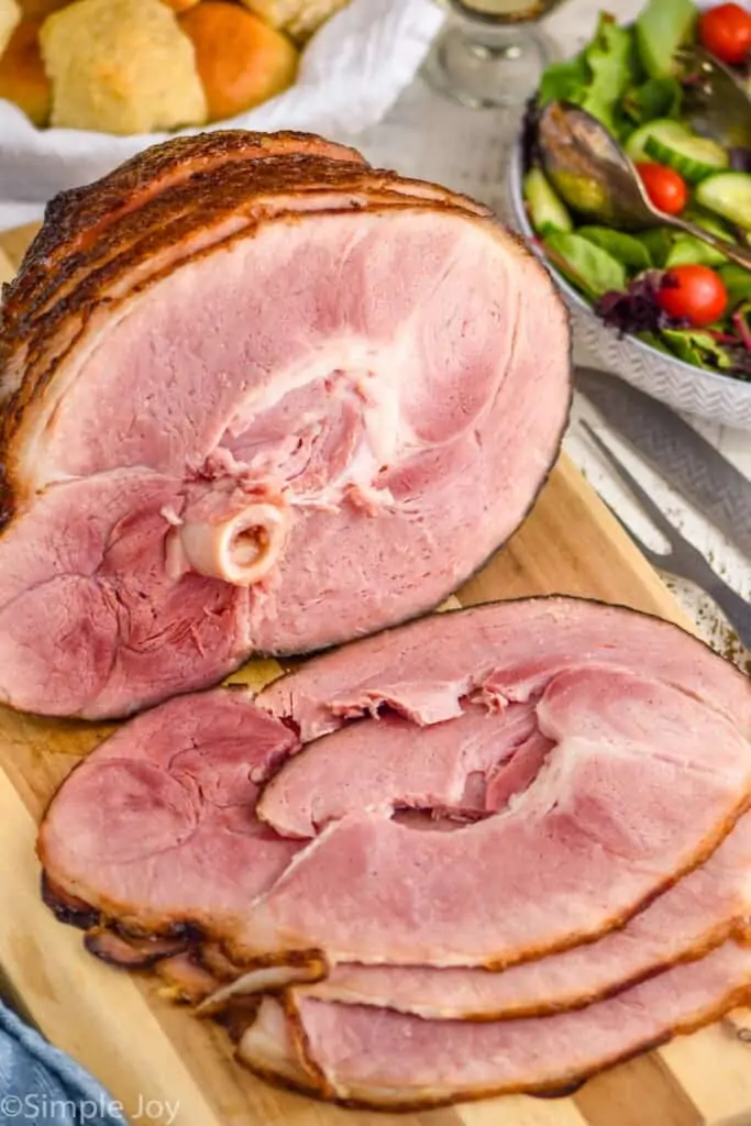 baked ham on a cutting board that has been sliced