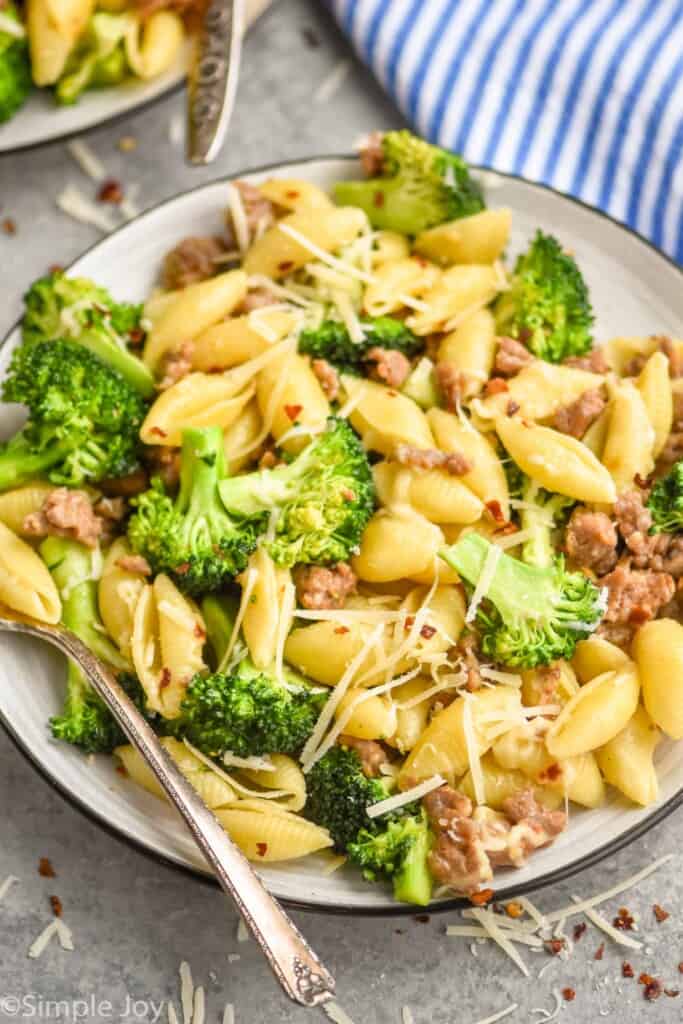 small plate full of broccoli pasta with sausage in it