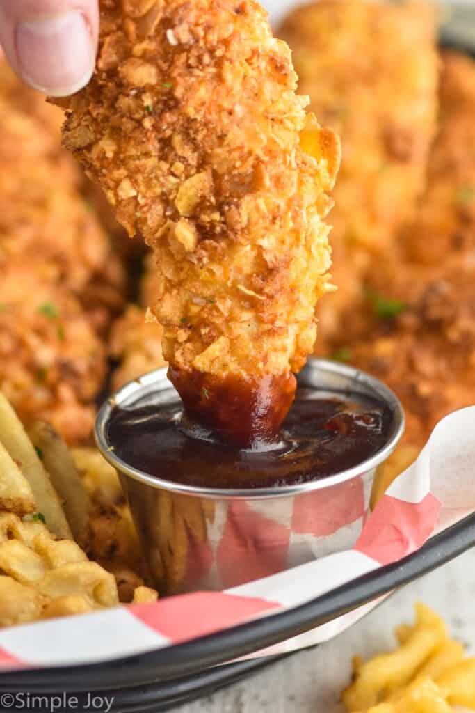 chicken strip being dipped into bbq sauce