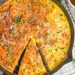 overhead of a frittata with a piece partially cut out, garnished with parsley and parmesan - 8