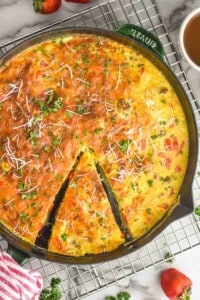overhead of a frittata with a piece partially cut out, garnished with parsley and parmesan