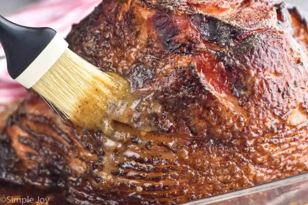 close up of ham glaze recipe being brushed on a spiral cut ham
