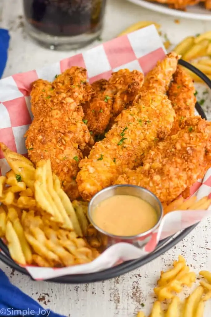 chicken tenders in a basket with fries and chick fil a sauce