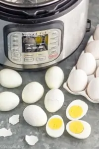 hard boiled eggs in front of an instant pot, some peeled, some cut in half
