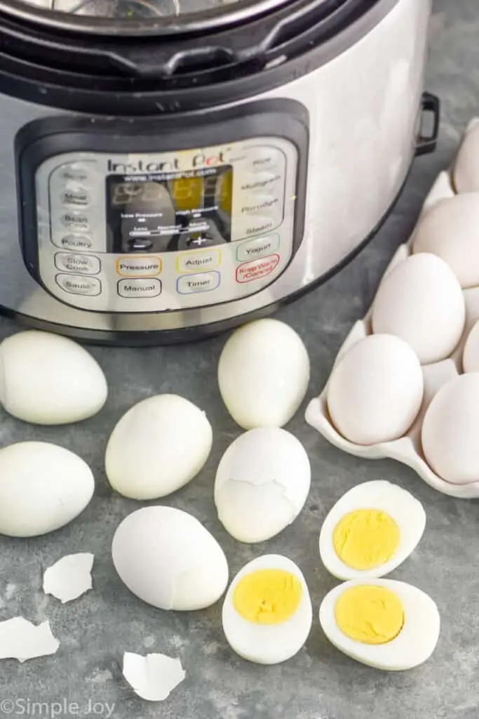 hard boiled eggs in front of an instant pot, some peeled, some cut in half