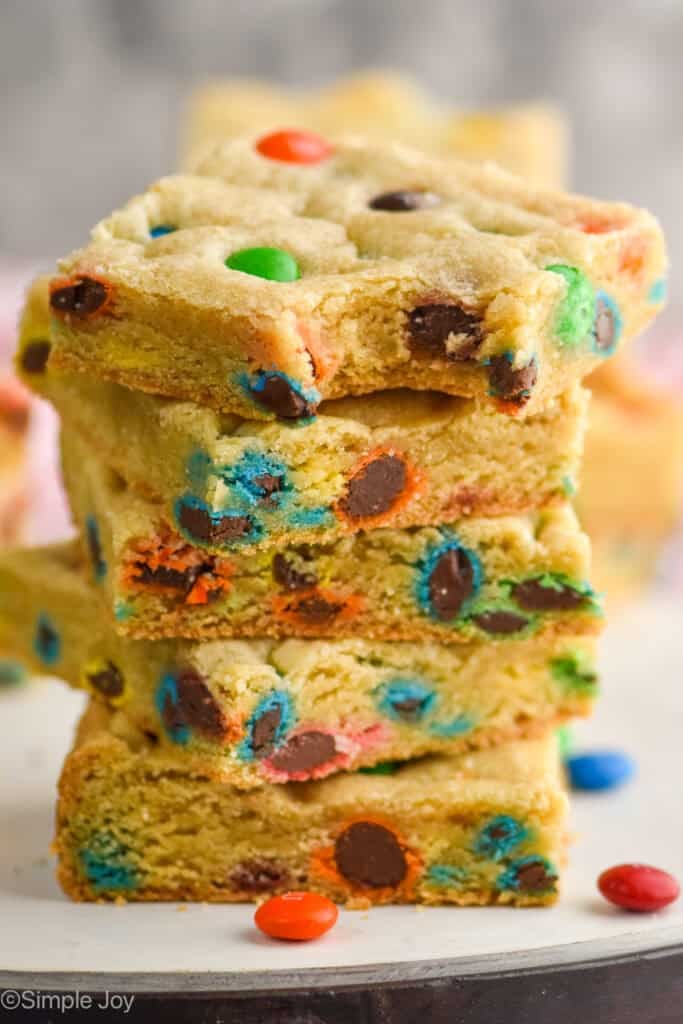 a stack of m&m cookie bars with a bite missing out of the top