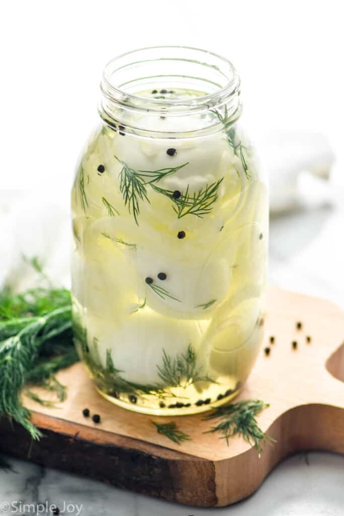 a jar of pickled egg recipe with fresh dill, onions, and pepercorns