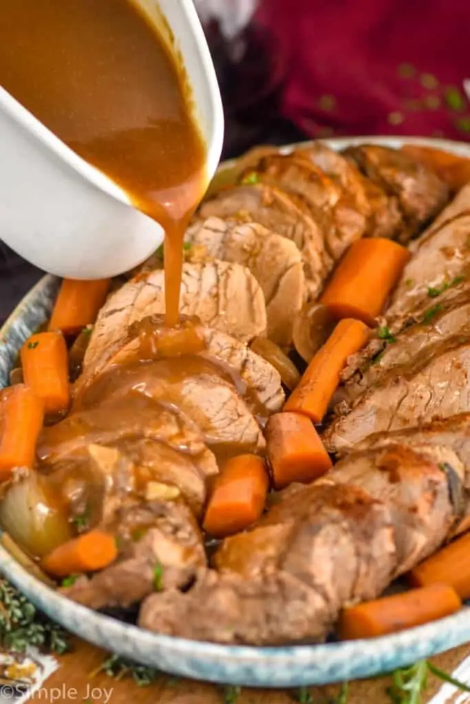 pork tenderloin on a platter with gray being poured over the top