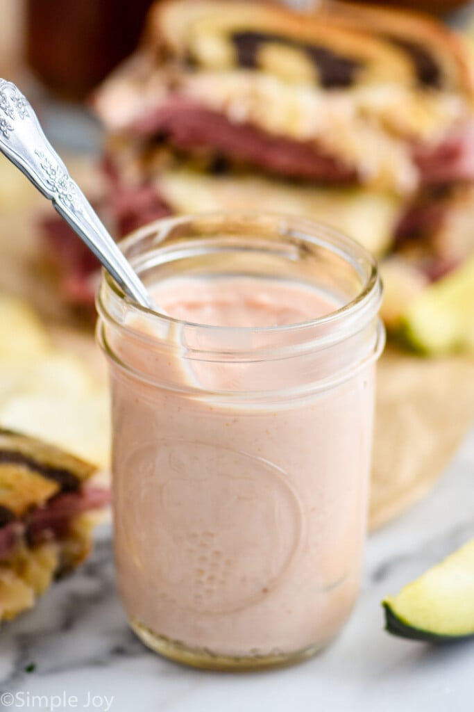 a mason jar of Russian Dressing with a Reuben Sandwich in the background
