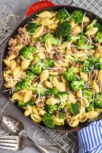 overhead view of sausage broccoli pasta topped with fresh parmesan and red pepper flakes