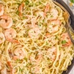 overhead of a skillet full of shrimp pasta garnished with parsley and parmesan