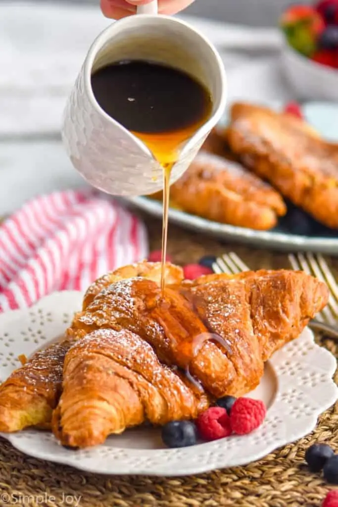 syrup being poured over croissants that have bee made into French toast