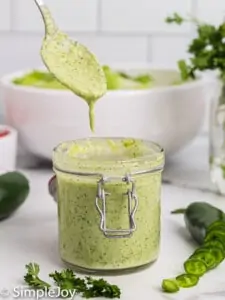 a small jar of jalapeno ranch dressing with a spoon dripping more over it