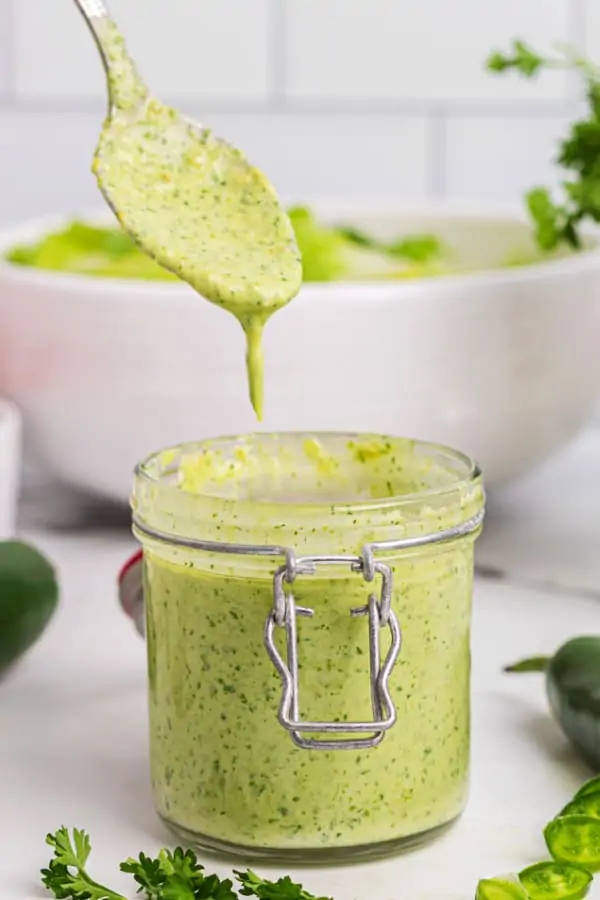 a small jar of jalapeno ranch dressing with a spoon dripping more over it