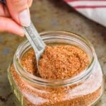 cajun seasoning mix in a small mason jar being spooned out with a tablespoon - 15