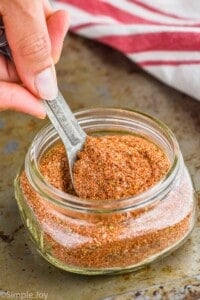 cajun seasoning mix in a small mason jar being spooned out with a tablespoon