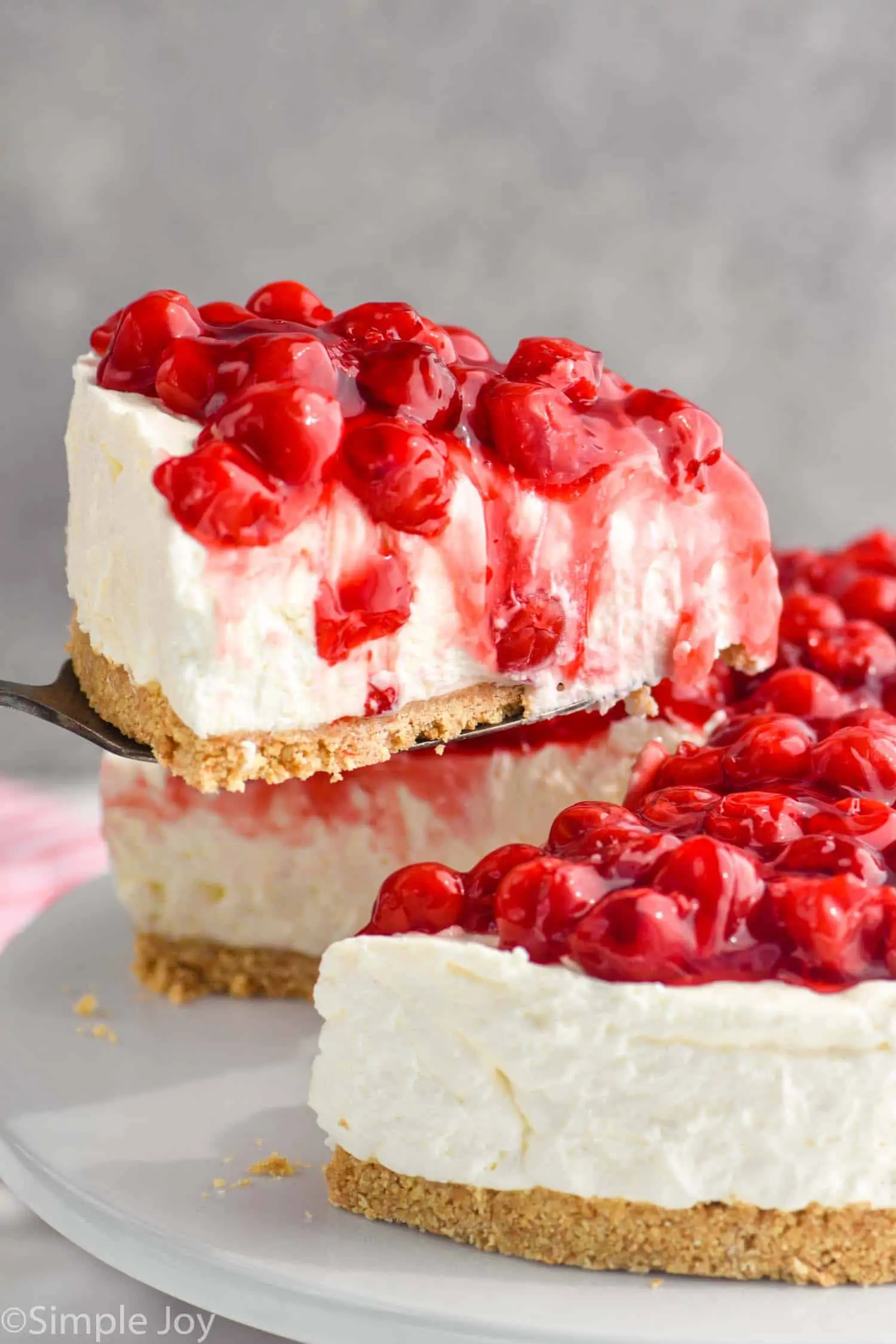 piece of cherry cheesecake being lifted out of a cheesecake