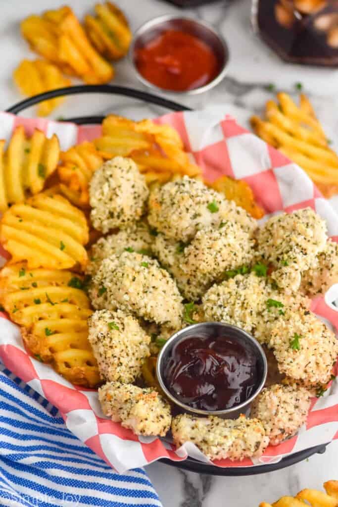 side view of basket of chicken nuggets with basket of fries