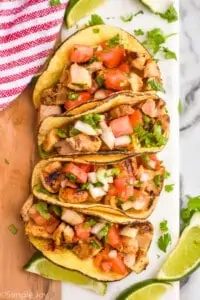 overhead of four street tacos on a board