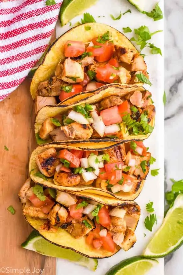 overhead of four street tacos on a board