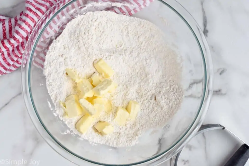 overhead of a bowl of flour with cubes of butter