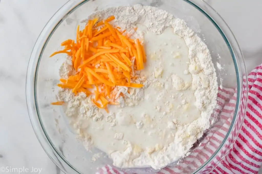 overhead of flour, buttermilk, and shredded cheddar cheese in a bowl